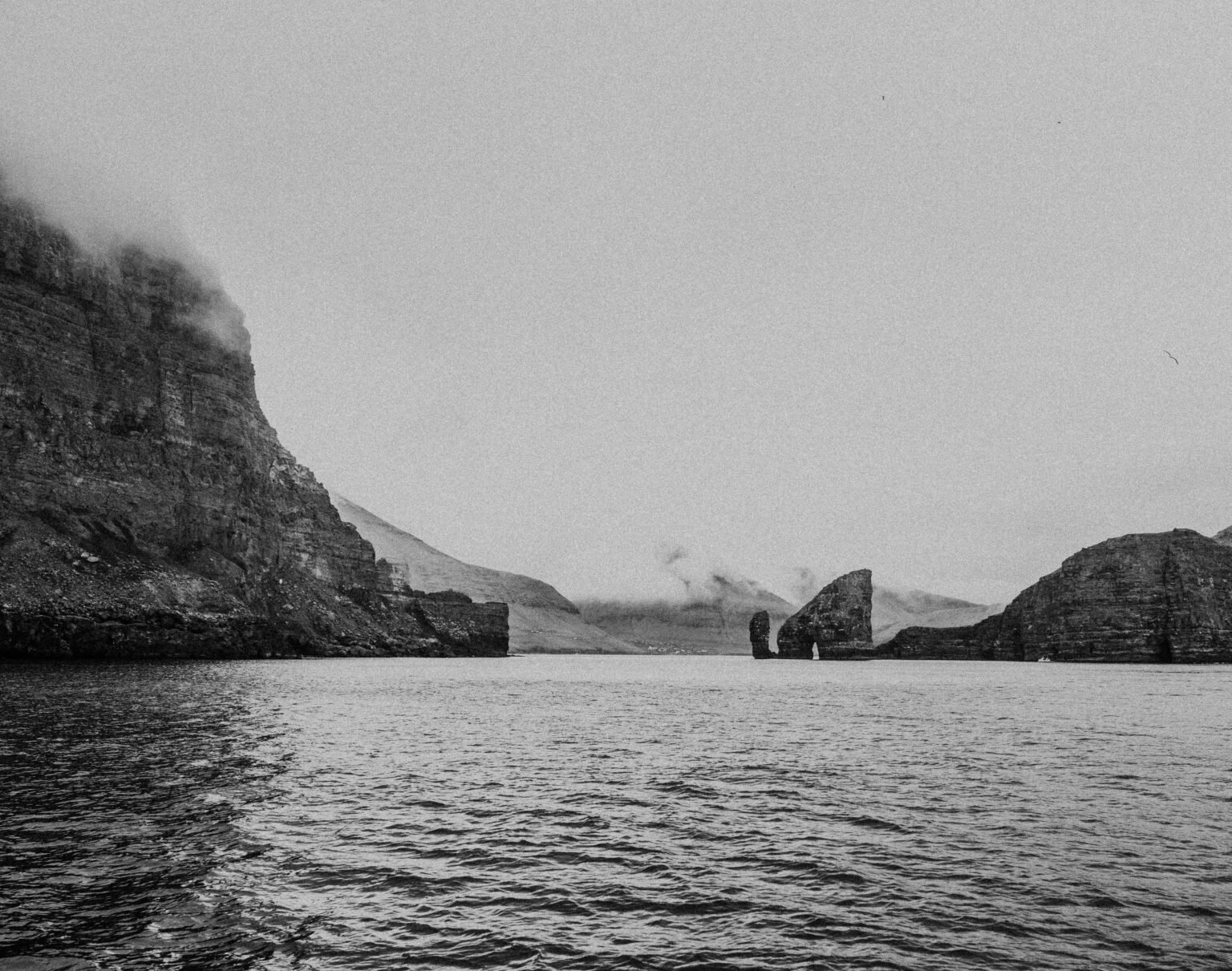 grayscale photo of body of water near mountain